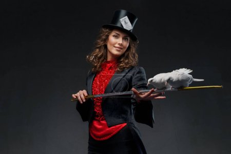 Téléchargez les photos : Image captivante d'une magicienne vêtue de magicien et coiffée d'un haut-de-forme noir, mettant en valeur ses talents de magicienne avec des colombes blanches gracieuses dans un mystérieux fond sombre - en image libre de droit
