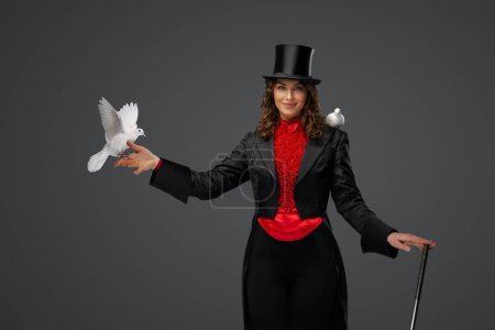 Téléchargez les photos : Performance mystique, magicienne et colombes blanches sur fond gris - en image libre de droit