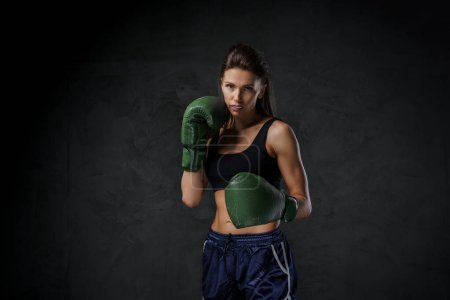Téléchargez les photos : Boxer femme en tenue de sport, affichant ses techniques de poinçon avec des gants, ensemble sur un fond lunatique - en image libre de droit