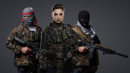 Téléchargez les photos : Trio d'extrémistes radicaux du Moyen-Orient vêtus de camouflage, de keffiyeh et de cagoule, posant sur un fond gris - en image libre de droit