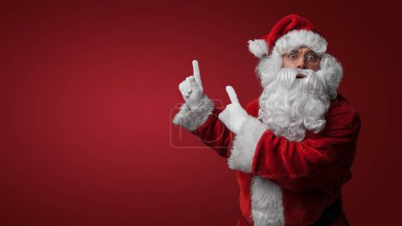 Photo for Surprised Santa Claus gesturing with both hands, expressing holiday excitement - Royalty Free Image
