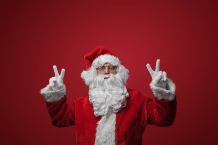 Téléchargez les photos : Père Noël avec des signes de paix, répandre la joie et l'amour sur Noël - en image libre de droit