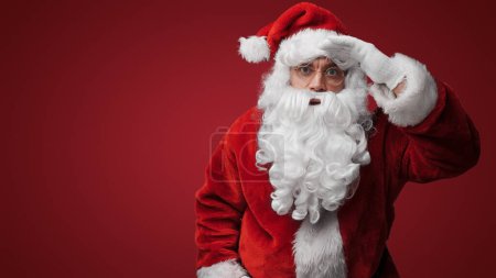 Photo for Thoughtful Santa Claus peering over glasses, searching for the naughty or nice - Royalty Free Image