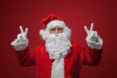 Téléchargez les photos : Père Noël avec des signes de paix, répandre la joie et l'amour sur Noël - en image libre de droit