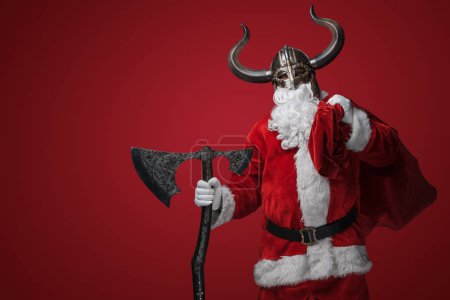 Foto de Santa Claus en un casco vikingo, empuñando un hacha decorativa, combinando tradición y fantasía - Imagen libre de derechos