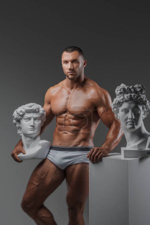 Foto de Belleza robusta: Hombre muscular y estatuas griegas antiguas - Imagen libre de derechos