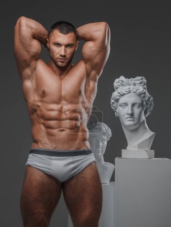 Foto de Belleza robusta: Hombre muscular y estatuas griegas antiguas - Imagen libre de derechos