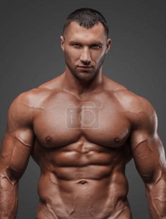 Porträt eines robusten Mannes mit gepflegtem Aussehen, weißen Slip und nacktem muskulösen Oberkörper vor grauem Hintergrund