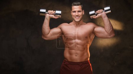 Photo for Fit male model lifting weights in a smoky, dark gym setting - Royalty Free Image