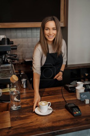 Foto de Amistoso camarero sirviendo café en cafeshop - Imagen libre de derechos