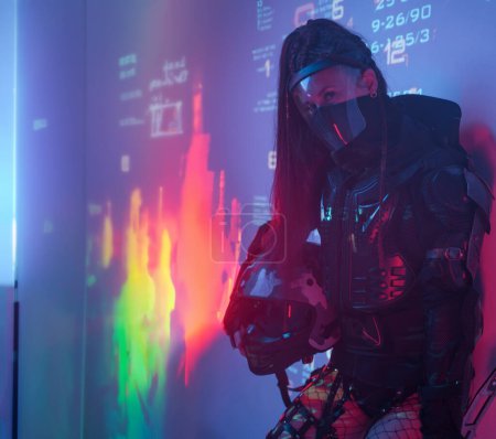 Téléchargez les photos : Une femme en costume noir tactique futuriste se dresse sur fond de symboles numériques projetés - en image libre de droit