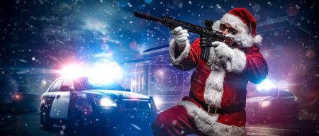 Photo for A man dressed as Santa Claus, holding a machine gun, poses in front of police cars with numerous police lights and sirens, amid a snowy stormy night on the street - Royalty Free Image