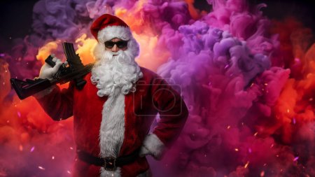 Foto de Un hombre vestido de Santa Claus, sosteniendo una ametralladora, posa sobre un fondo de humo brillante y multicolor de una granada de humo, con chispas de colores volando en el aire - Imagen libre de derechos