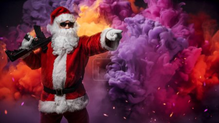 Téléchargez les photos : Un homme habillé du Père Noël, armé d'une mitrailleuse, pointe son doigt dans une direction, posant au milieu d'une fumée vibrante et multicolore avec des étincelles colorées dans l'air - en image libre de droit