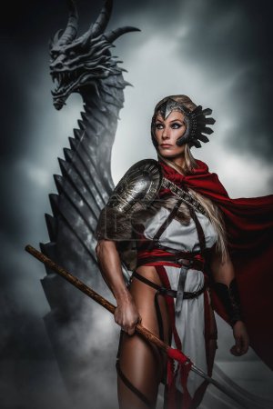 A fierce warrior woman stands with a spear before a menacing dragon, exuding confidence and strength against a stormy backdrop