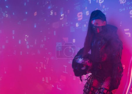 Foto de Una mujer con un traje negro táctico futurista se levanta contra un telón de fondo de símbolos digitales proyectados - Imagen libre de derechos