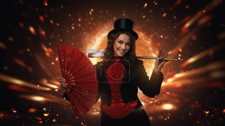 Téléchargez les photos : Magicien élégant avec chapeau haut de forme performant avec feu et ventilateur - en image libre de droit