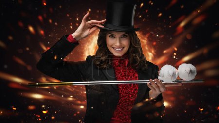 Photo for Smiling magician tipping hat with doves on wand, fiery backdrop - Royalty Free Image