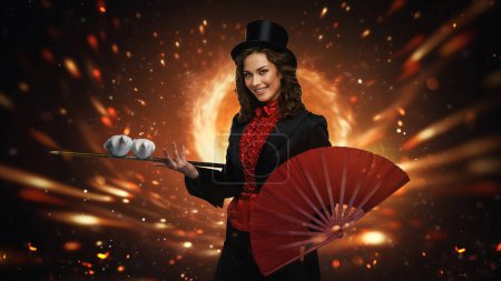 Téléchargez les photos : Magicien élégant avec chapeau haut de forme performant avec feu et ventilateur - en image libre de droit