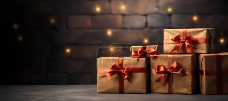 Téléchargez les photos : Boîtes cadeaux festives avec emballage doré et rubans élégants contre un mur de briques bokeh chaud. - en image libre de droit