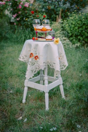 Foto de Mesa con regalo festivo y mantel en el jardín de verano - Imagen libre de derechos