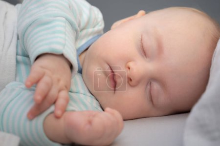 Photo for Carefree sleep little baby boy in his bed in room. Peaceful child lying on bed with closed eyes. Closeup portrait. - Royalty Free Image