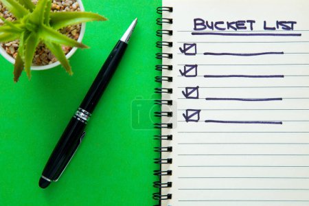 Bucket list on notebook with a pen on green background