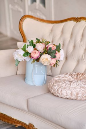 Duży bukiet dekoracyjnych kwiatów w różowym pudełku kapelusz w luksusowym wnętrzu piękne klasyczne białe wnętrze z białą sofą. Wiosna, kwiaty, prezenty, dekoracje