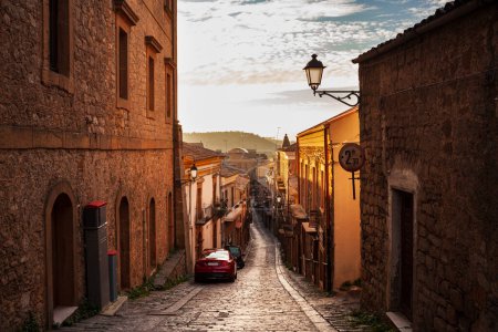 Rue avec vieilles maisons d'Aidone au coucher du soleil dans la province d'Enna, Sicile en Italie