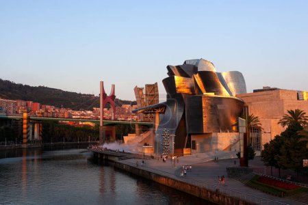 Foto de Bilbao, España - 02 de agosto de 2022: Vista al atardecer del Museo Guggenheim de arte moderno y contemporáneo y del puente La Salve - Imagen libre de derechos