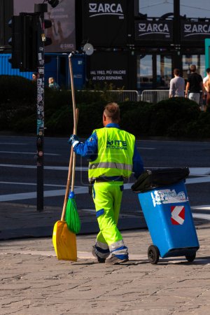 Photo for Trieste, Italy - September 30, 2023: A man dressing yellow uniform picking up rubbish, cleaning up streets. Scavenger, dustman, garbage collector, ashman - Royalty Free Image