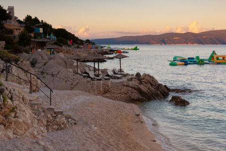 Strohschirme am Strand von Rabac, einem kroatischen Ferienort an der Kvarner Bucht, südöstlich von Labin, in Istrien. Rabac war lange Zeit ein kleiner Fischerhafen und hat sich in den letzten Jahren zu einem Kurort entwickelt.