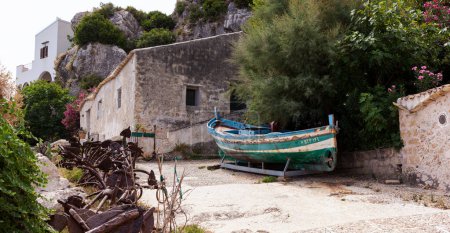 Foto de Antiguo barco en el patio de la antigua Tonnara di Scopello con las anclas de hierro una vez utilizado para la colocación de la trampa de atún, Sicilia - Imagen libre de derechos