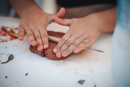 Téléchargez les photos : Gros plan des mains d'enfants modelant l'argile - en image libre de droit