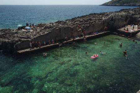 Téléchargez les photos : Marina Serra, Italie - Juillet 2023 : Les gens et les enfants profitent d'une piscine naturelle de la mer - en image libre de droit