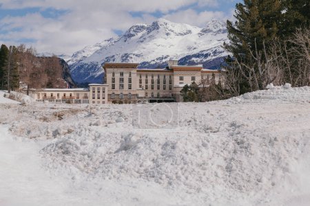 Maloja, Switzerland - March 2024: The architecture of the elegant Maloja Palace Hotel surrounded by snowy mountains 