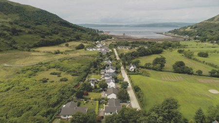Escocia vista aérea: destilería de whisky Loch Ranza, pueblo verde, valle de la montaña, ciudad de camping. Hermoso paisaje en Lochranza Bay, Arran Island, Reino Unido. Filmación