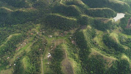 Rural green mountains ranges aerial view: greenery road and cottages at hilly countryside of Legazpi, Philippines. Small houses and way on hillside grass valley. Epic nature landscape. Soft light shot