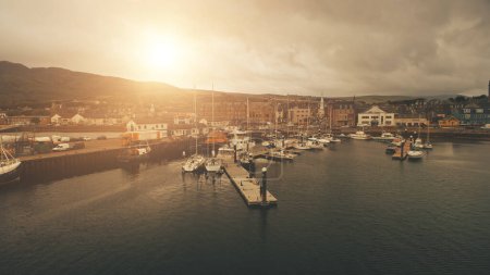 Sun over ships, yachts at sea bay aerial. Port cityscape with ancient architecture landmark at ocean coast of Campbeltown, Scotland, Europe. Urban streets with old buildings at traffic highway