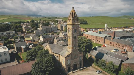 Closeup historic church with clock tower aerial. Ancient chapel at Campbeltown city, Scotland, Europe. Historical architecture landmark. streets with old buildings. European town cityscape attraction