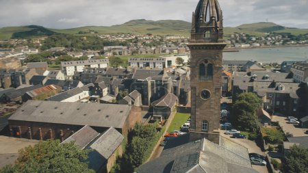 Closeup historic church with clock tower aerial. Ancient chapel at Campbeltown city, Scotland, Europe. Historical architecture landmark. streets with old buildings. European town cityscape attraction