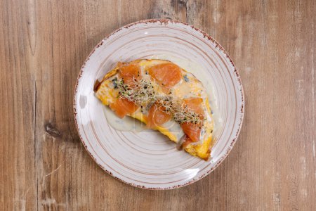 Photo for Fried eggs with salmon and sprouted grains on a round ceramic plate on a wooden table - Royalty Free Image
