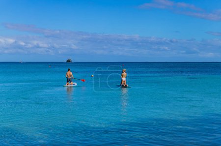 Photo for Viti Levu, Fiji: happy couple enjoying stand up paddling during summer vacation. Viti Levu, Fiji - Royalty Free Image