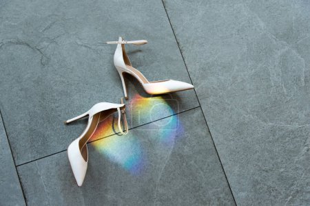 Foto de Elegantes zapatos blancos clásicos de las mujeres en el suelo. Bengala arco iris. - Imagen libre de derechos