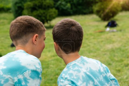 Foto de Two happy boys, happy brothers, view from the back. Brothers play outdoors in summer, best friends. Conspirators, mystery. - Imagen libre de derechos