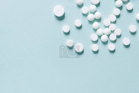 Photo for Scattered white pills on blue table. Mock up for special offers as advertising, web background or other ideas. Medical, pharmacy and healthcare concept. Copy space. Empty place for text or logo - Royalty Free Image