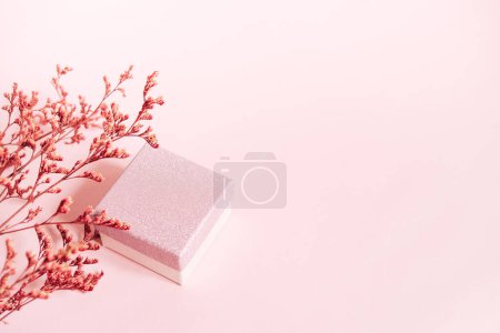 Foto de Festive pink background with a gift and a branch of flowers. Happy mother's day, women's day or birthday in pastel colors. Mockup. copy space - Imagen libre de derechos