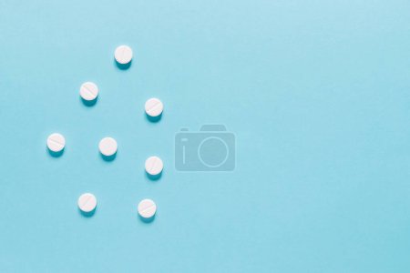 Téléchargez les photos : Scattered white pills on blue background. Mock up for special offers as advertising, web background or other ideas. Medical, pharmacy and healthcare concept. copyspace. Empty place for text or logo - en image libre de droit