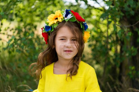 Ukrainian child girl wearing national clothes with embroidery and wreath of flowers outdoor. Ukraines Independence, Flag Day, Constitution day. Child in nature.