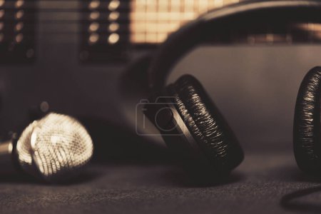 Foto de Guitarra eléctrica negra con auriculares y micrófono sobre fondo oscuro para temas musicales y dibujos. Equipo de compositor de música - Imagen libre de derechos